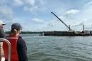 Laura Brown (left), owner of Fox Point Oysters, and Ray Grizzle, a UNH professor of biological sciences, watch as a crane operated by Riverside & Pickering Marine Contractors deposits oyster shells at the Nannie Island reef restoration site.